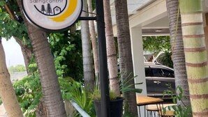 A sign for "Ilavoun's Soengchanthir" with a logo, set against a backdrop of palm trees and a parked car. - Saengcanthr (Nakhon Ratchasima)