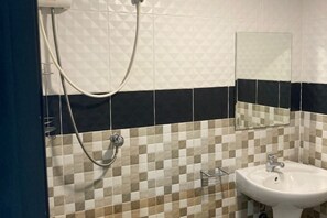 A bathroom with a checkered tile wall, a white sink, a mirror, and a shower head. - Saengcanthr (Nakhon Ratchasima)