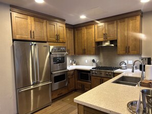 A modern kitchen with stainless steel appliances, wooden cabinets, and a granite countertop.