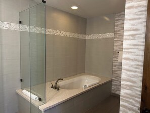 Un baño moderno con ducha envuelta en cristal, una bañera independiente y suelo de baldosas.