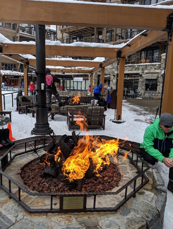 Relax by the central fire feature in a sheltered outdoor seating area surrounded by stone walls and benches.
