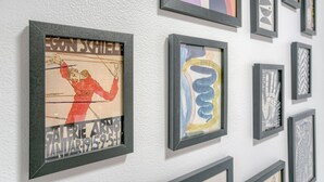 Een muur met verschillende kunstwerken in lijsten.