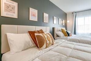 Une chambre d’hôtel avec deux lits, une tête de lit et des œuvres d’art encadrées accrochées au mur.