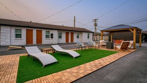 Een gebouw met een overdekt terras, een gazon en een verhard pad.