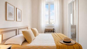 A hotel room with a bed, a nightstand, a window with curtains, and a view of the outside. - Michelangelo Prestige Apartment Vatican View by RHR (ROMA)