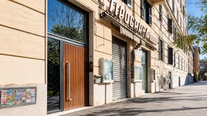 A building with a large wooden door, a sign reading 'TIPOGRA A CARTO', and a window with a poster. - Michelangelo Prestige Apartment Vatican View by RHR (ROMA)