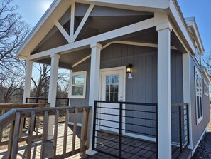 A small, single-story building with a porch, a gated entrance, and a light fixture above the door.