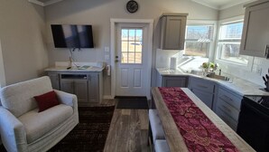 Un espacio habitable compacto con kitchenette, un sofá, un televisor de pantalla plana y un comedor.