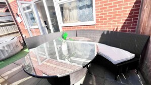 Un tavolo con piano in vetro, un divano in vimini e una pianta in vaso.