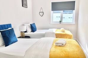 A hotel room with two beds, one with a yellow bedspread and the other with a white bedspread. There is a window with a view of the sea and a plant on the windowsill. - House - Sleeps 12 - Hot tub - Pool Table - Parking (Canterbury)