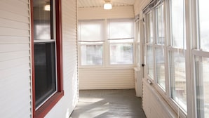 A narrow corridor with white siding and a wooden floor, leading to a door with a window. - Spacious 5-bedroom house with Wi-Fi and washer/dryer in convenient South Omaha (Omaha)