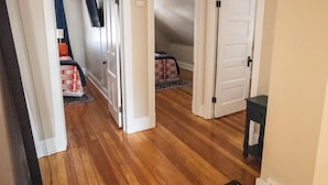A hallway with wooden flooring, white doors, and a ceiling light fixture. - Spacious 5-bedroom house with Wi-Fi and washer/dryer in convenient South Omaha (Omaha)