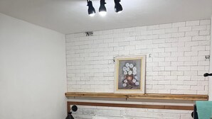 A bedroom with a bed, white brick-patterned wall, a framed floral artwork, and a wooden headboard. - Colinna Hostel (Rio de Janeiro)