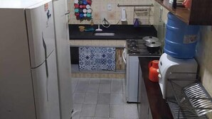 A compact kitchen with a refrigerator, stove, and various kitchen utensils. - Colinna Hostel (Rio de Janeiro)