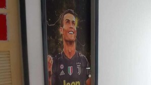 A framed portrait of a person in a sports jersey with the word "Jeep" on it, mounted on a wall in a hallway with patterned flooring. - Colinna Hostel (Rio de Janeiro)