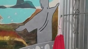 A room with a mural of a person with arms outstretched, a red hammock, and a barred window. - Colinna Hostel (Rio de Janeiro)