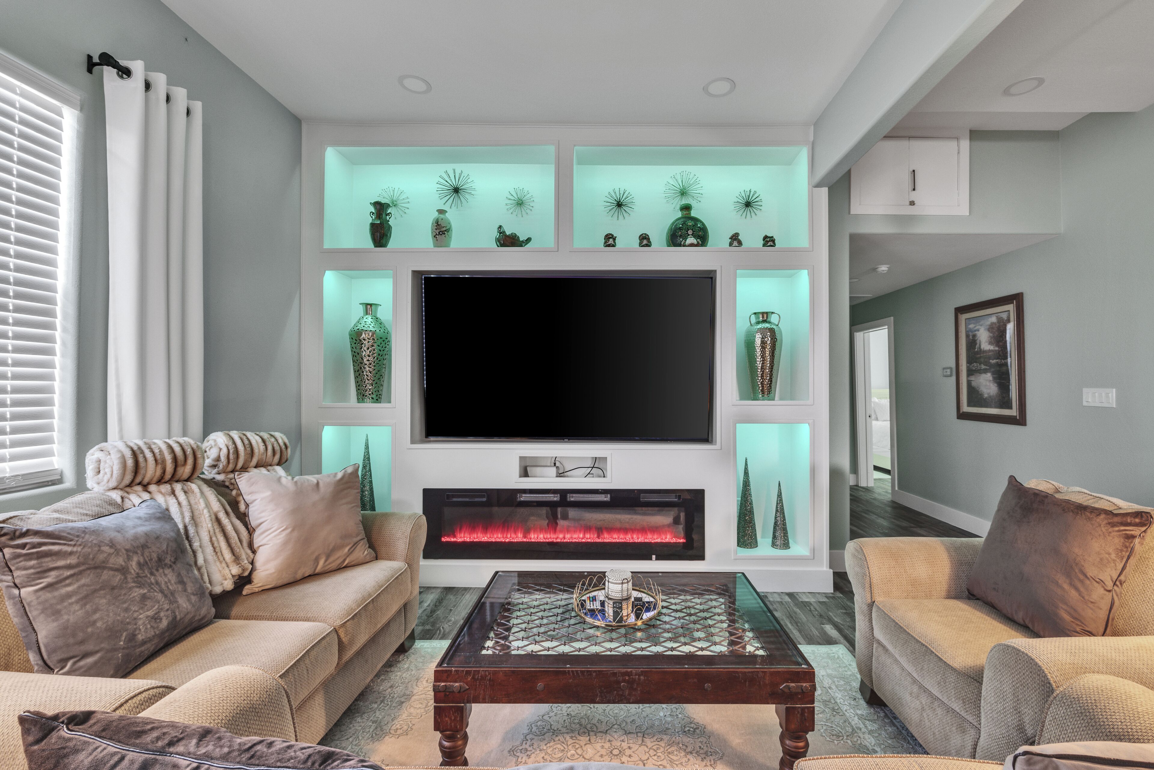 Una sala de estar con una televisión de pantalla plana, chimenea y estanterías decorativas.