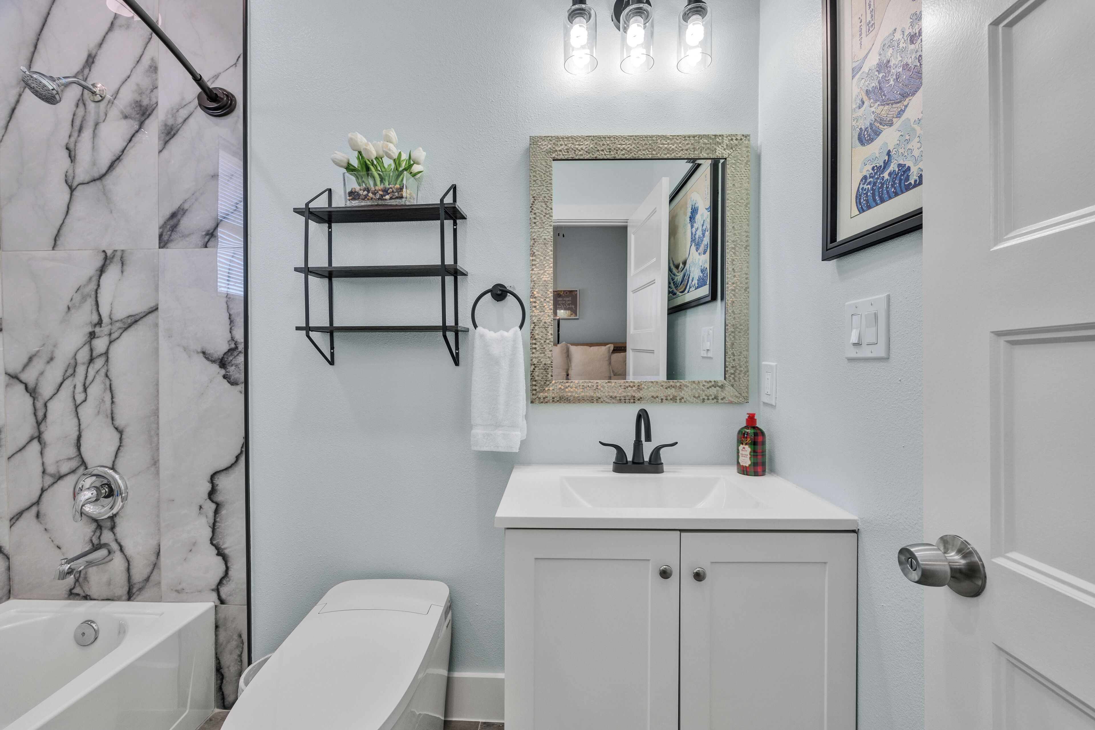 A bathroom with a bathtub, a sink, a mirror, and a shower.