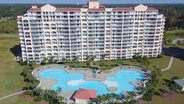 Un grand hôtel doté de nombreux balcons et d’une piscine centrale.