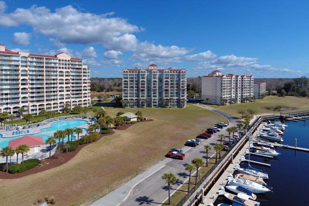 Een resort met meerdere hoge gebouwen, een zwembad en een jachthaven met boten.