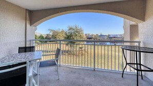 Un balcon avec une table et des chaises, une vue sur un lac et un bâtiment en arrière-plan.