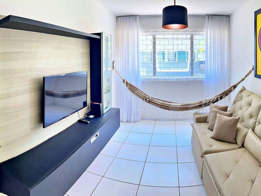 Una sala de estar moderna con un televisor de pantalla plana, un sofá color beige, una hamaca y un cuadro abstracto y colorido.