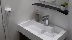 A bathroom with a white sink, a mirror, a shelf with a plant, and a toilet. - Camping Charlieu - Nos Studios (Charlieu)