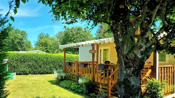A wooden cabin with a deck, surrounded by a well-maintained lawn and hedges. - Camping Charlieu - Nos Studios (Charlieu)