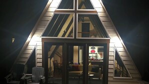 A triangular attic with a glass door entrance, a staircase leading to the upper floor, and a visible kitchen area.