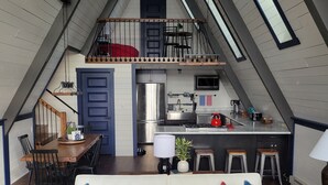 A loft-style living space with a dining area, kitchen, and a staircase leading to an upper level.