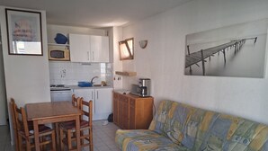 A compact living space with a dining area, kitchenette, and a sofa.