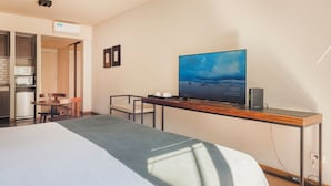A hotel room with a bed, a TV on a wooden desk, a microwave, and a small kitchen area. - Modern Premium Studio T310 (Buenos Aires)