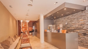 A hotel lobby with a reception desk, a seating area with benches, and a stone wall. - Modern Premium Studio T310 (Buenos Aires)