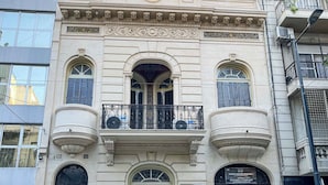 A building with a classic architectural style, featuring arched windows and a balcony with ornate metal railings. - Maison Thames by Argenhost (Buenos Aires)