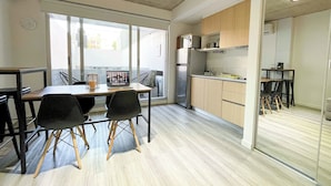 A modern kitchen with a refrigerator, stove, and wooden cabinets. There is a dining table with chairs and a laptop on it. - Maison Thames by Argenhost (Buenos Aires)