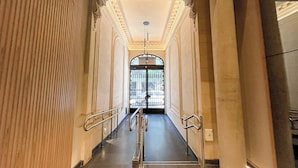 A grand hallway with a polished floor, ornate columns, and a large arched doorway at the end. - Maison Thames by Argenhost (Buenos Aires)