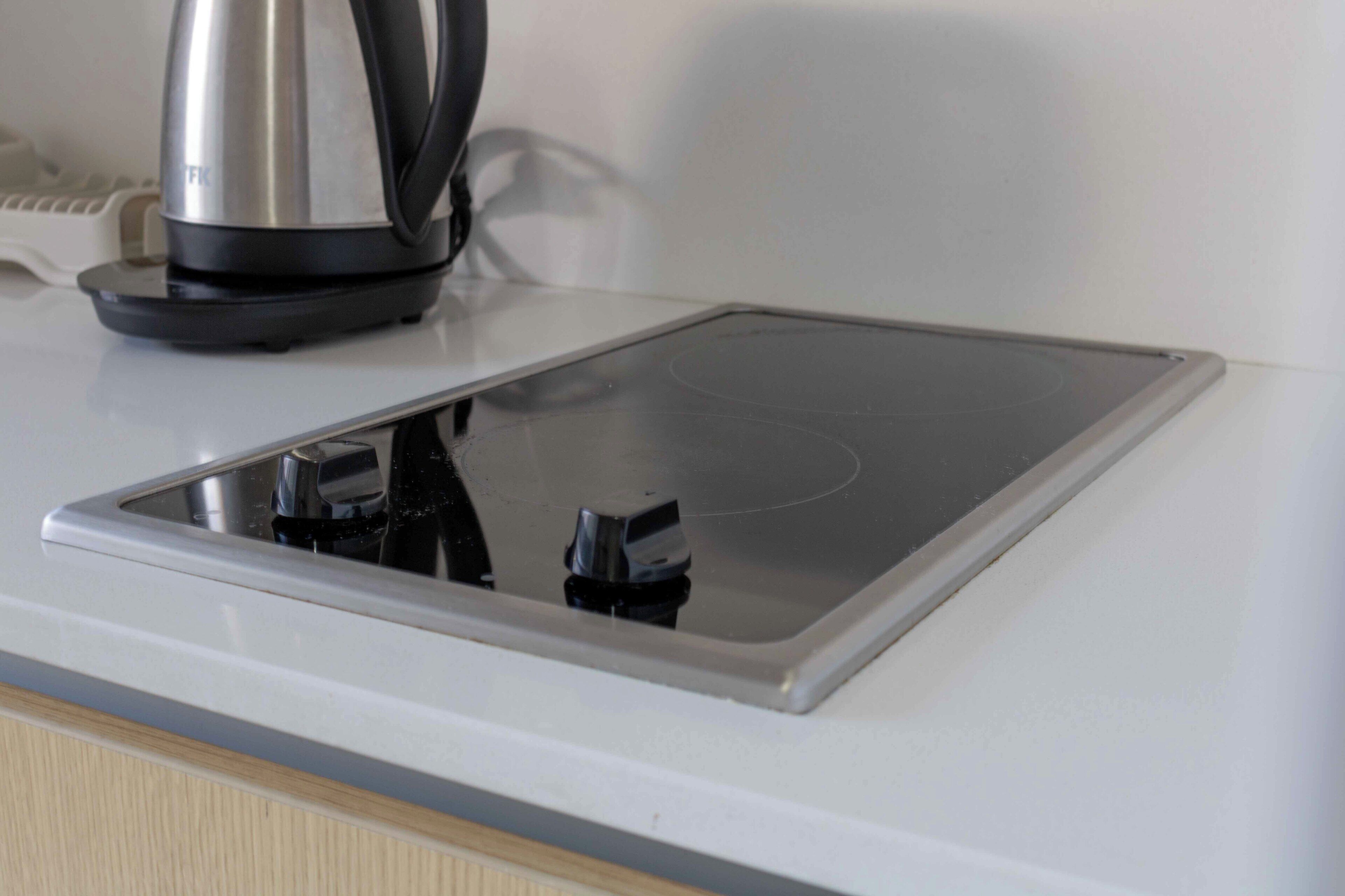 A kitchen with a built-in induction cooktop and a kettle on the counter.