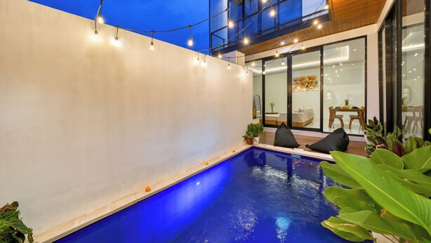 A modern outdoor pool area with string lights, a wooden deck, and a glass-enclosed dining area. - Cozy 3bedroom villa Bliss, Close to Canggu,
King bed,Tranquil! (Bali)