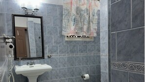 Een badkamer met een wastafel op een voetstuk, een toilet en een douchecabine.