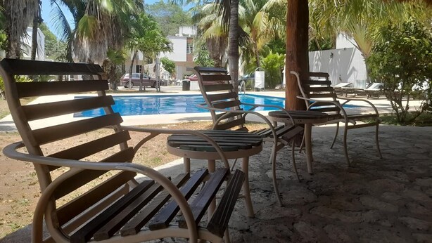 A poolside area with lounge chairs and a thatched roof structure. - Beach house with jacuzzi (Playa del Carmen)