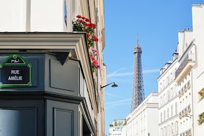 Vista de calle con un cartel que indica 'RUE AMÉLIE' y la Torre Eiffel al fondo.