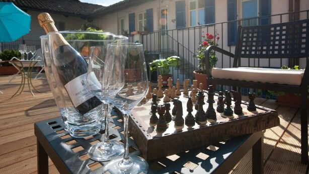 A chessboard on a table with a bottle of champagne and glasses. - Apartment with garage - La Rosa nel Borgo (La Morra)
