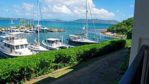 Ein Yachthafen mit vertäuten Booten, umgeben von viel Grün und freiem Blick auf das Meer.