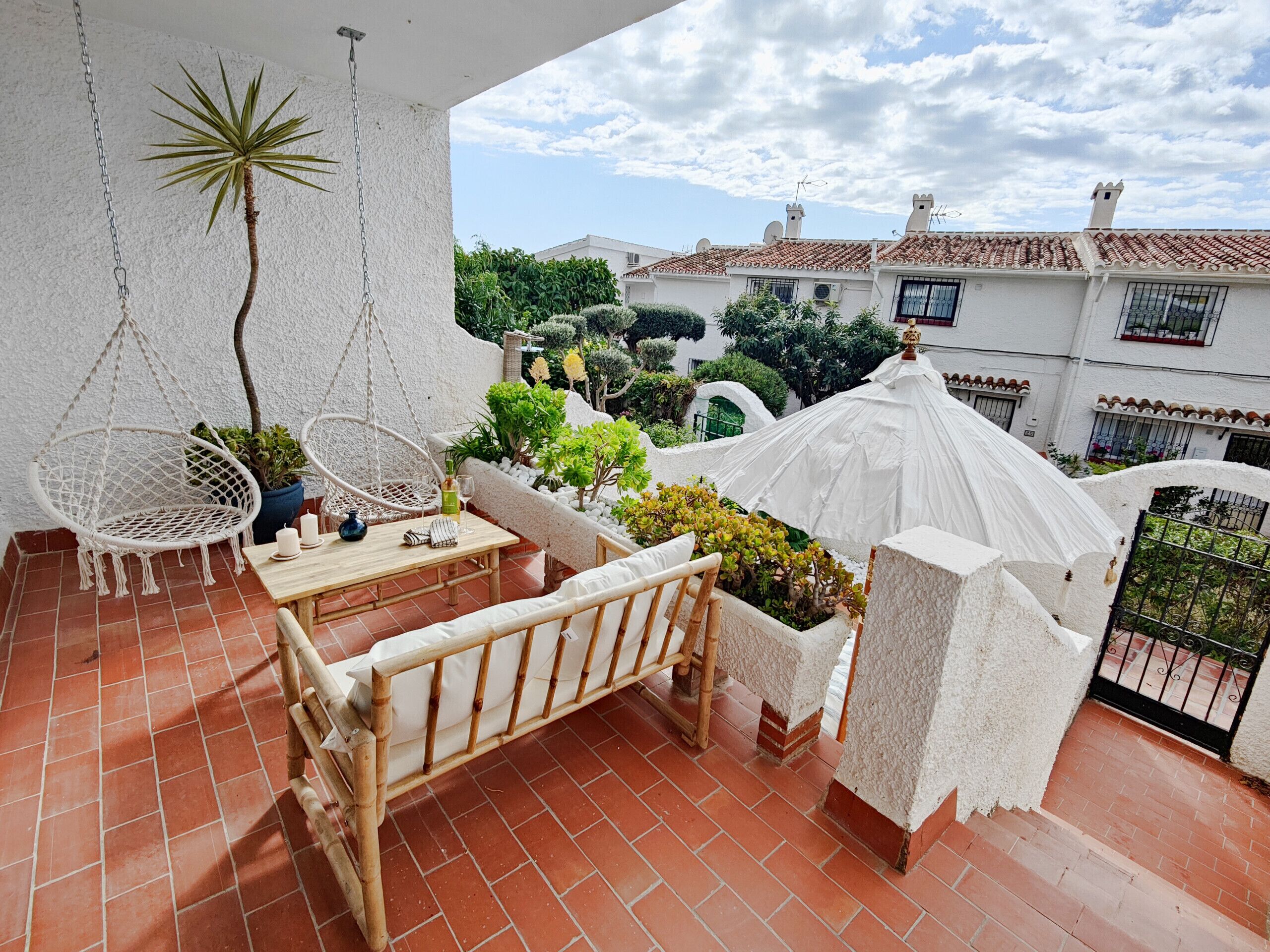 A terrace with a hanging chair, a small table, and a cushioned bench.