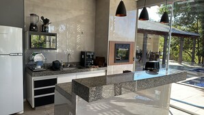 A modern kitchen with granite countertops, a built-in coffee maker, and a large window overlooking a pool area.