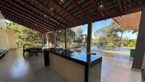A covered outdoor area with a pool, a dining table, and chairs.