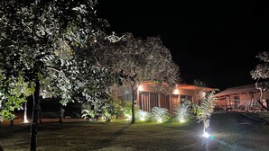 A well-lit outdoor area with a building, trees, and a lawn.