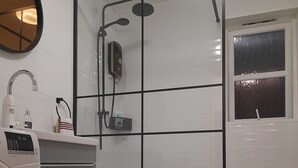 Ein Badezimmer mit Dusche, Toilette und Waschmaschine.