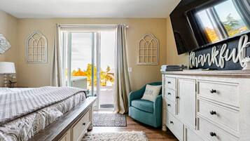 Un dormitorio con cama, televisor, cómoda y vistas al exterior.
