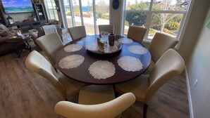Un comedor con una mesa redonda, sillas color beige y vistas al exterior a través de amplios ventanales.